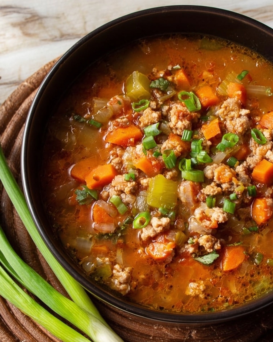 A close-up view of a black bowl filled with chunky soup resting on a brown woven mat placed on a white marbled surface. The soup has visible layers of bright orange carrot slices, light green celery pieces, and small crumbled bits of cooked ground meat mixed into a rich, light brown broth. The top is garnished with chopped fresh green onions scattered across the surface. Three long green onion stalks lie beside the bowl on the white marbled surface. Photo taken with an iphone --ar 4:5 --v 7
