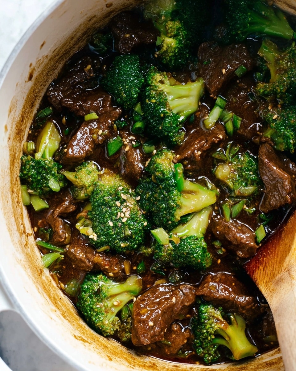 The image shows a close-up of beef and broccoli cooked dish in a white pot. The dish has two main layers: bright green broccoli florets and chunks of dark brown beef mixed together in a shiny, thick sauce that has a slightly oily texture. Small sesame seeds and bits of green onion are sprinkled evenly throughout the dish. A wooden spoon is partially visible stirring the food at the bottom right corner. The pot's inner edge shows some sauce stains, adding to the cooked, savory look of the dish, all set on a white marbled texture surface. photo taken with an iphone --ar 4:5 --v 7