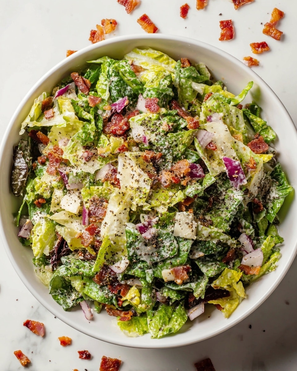 A top-down view of a white bowl filled with a fresh chopped salad showing about three layers; the base layer is made of mixed leafy greens with different textures and shades of green, the middle layer contains chunks of red onion, small pieces of crispy bacon, and bits of diced white cabbage, and the top layer is sprinkled with grated cheese and black pepper giving a speckled effect over the colorful salad. Some bacon bits are scattered around the bowl on a white marbled surface. photo taken with an iphone --ar 4:5 --v 7