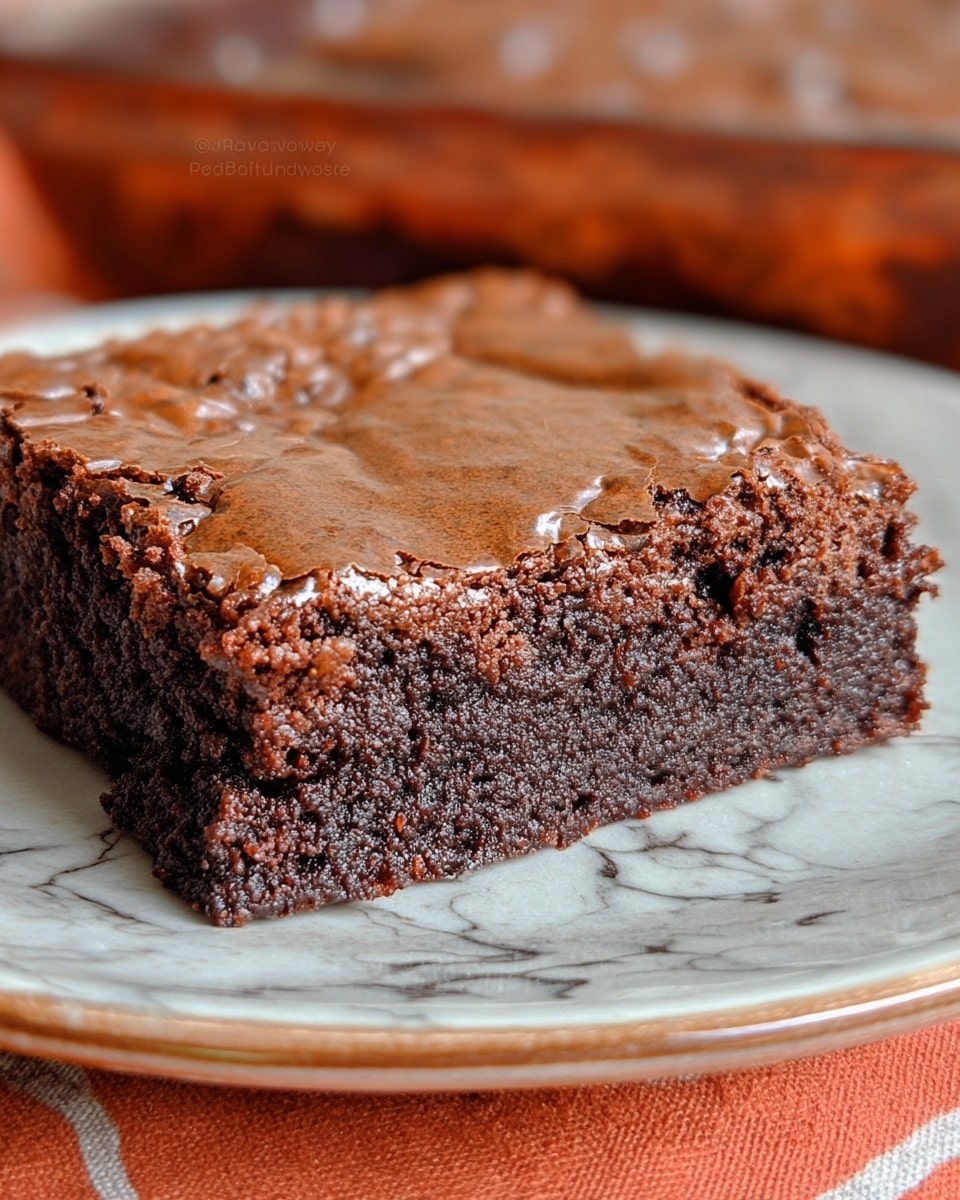A close-up view of a single square brownie resting on a white plate with a shiny, cracked top layer showing a slightly crispy texture, beneath it is a thick, dense, and moist dark brown chocolate layer with small bits visible inside, all set against a white marbled surface. photo taken with an iphone --ar 4:5 --v 7
