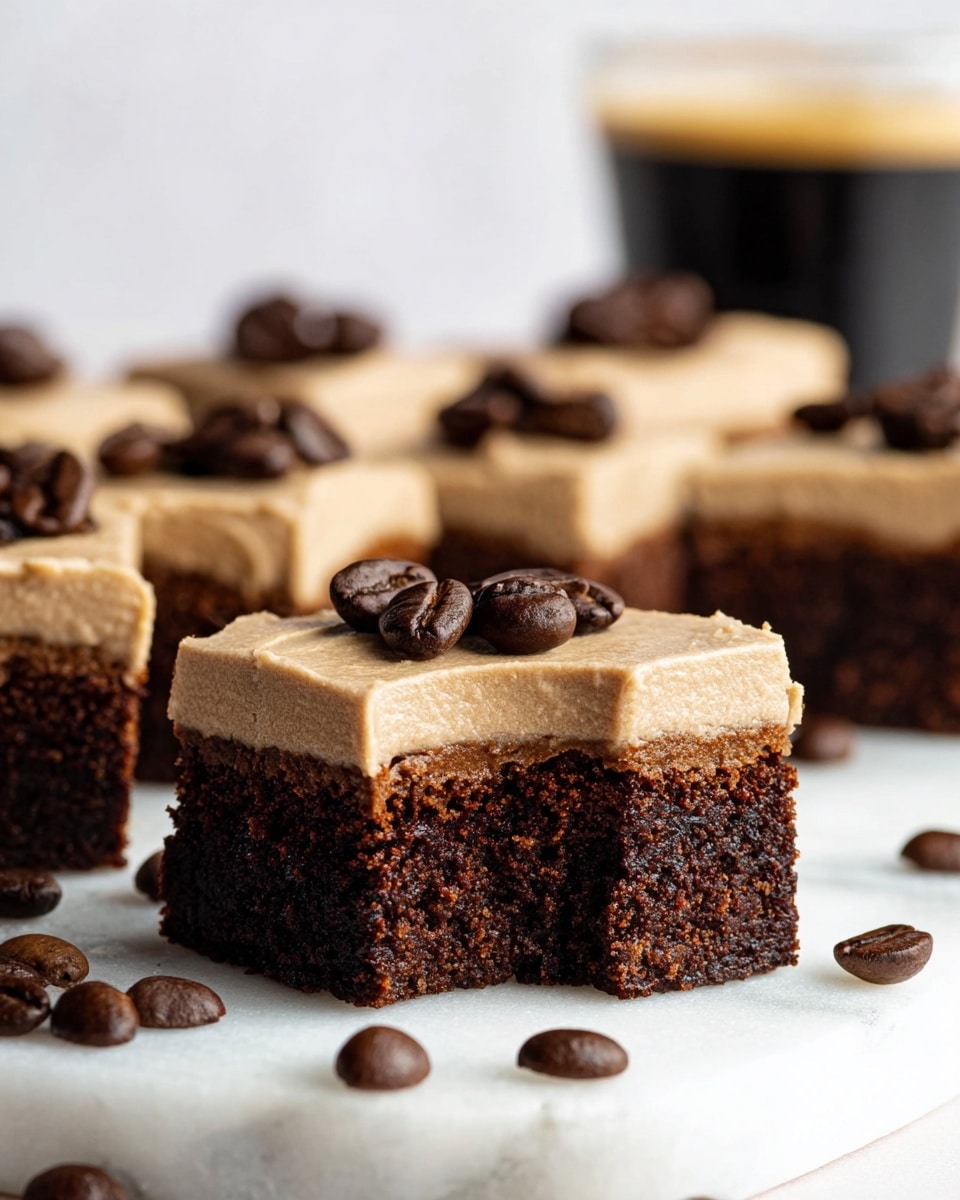 The image shows a close-up of several small square brownies on a white marbled surface. Each brownie has two layers: a bottom dark brown layer that looks chewy and thick, and a top light brown layer that is smooth and creamy, resembling frosting. On top of the frosting, there are a few coffee beans placed as decoration. One brownie in the front has a bite taken out, showing the dense texture clearly. More coffee beans are scattered around the brownies, adding to the coffee theme. The background is simple and softly blurred, bringing focus to the brownies. photo taken with an iphone --ar 4:5 --v 7
