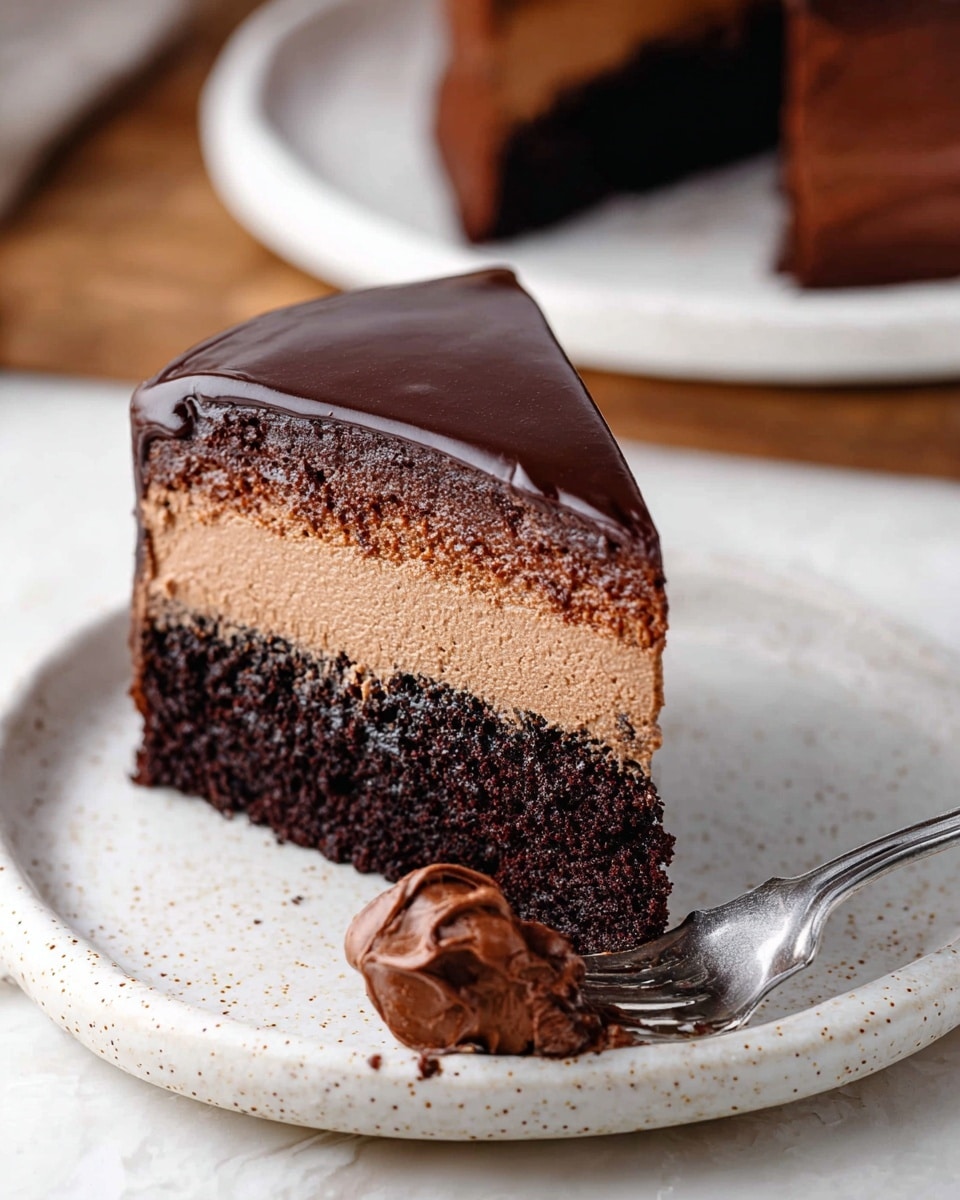 The image shows a rich chocolate cake with three clear layers: a dark, dense chocolate base, a thick middle layer of smooth chocolate mousse in a lighter brown shade, and a shiny, glossy chocolate glaze on top that gently drips down the sides. The cake is sliced, and one triangular piece is lifted with a silver spatula, showing the smooth textures clearly. The cake sits on a round white plate placed on a white marbled surface, with a few stacked white plates blurred in the background. Photo taken with an iphone --ar 4:5 --v 7