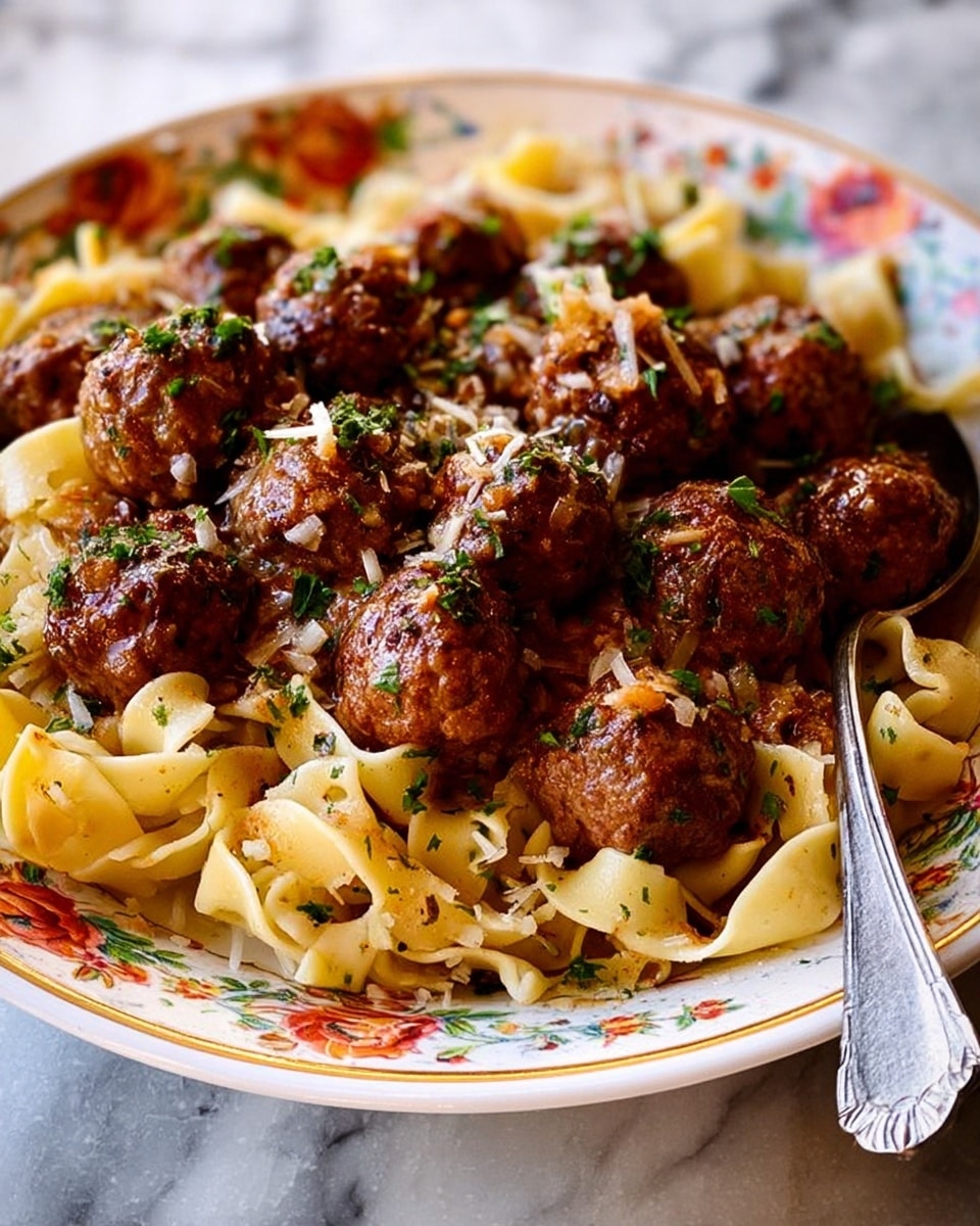 A white plate with an orange decorative rim holds a dish of brown meatballs on top of curly yellow pasta noodles coated in a light brown sauce. The meatballs are round, juicy, and sprinkled with small green herbs. The pasta is twisted and mixed evenly beneath the meatballs. A metal fork is partially visible on the right side of the plate. The plate is set on a white marbled surface. photo taken with an iphone --ar 4:5 --v 7