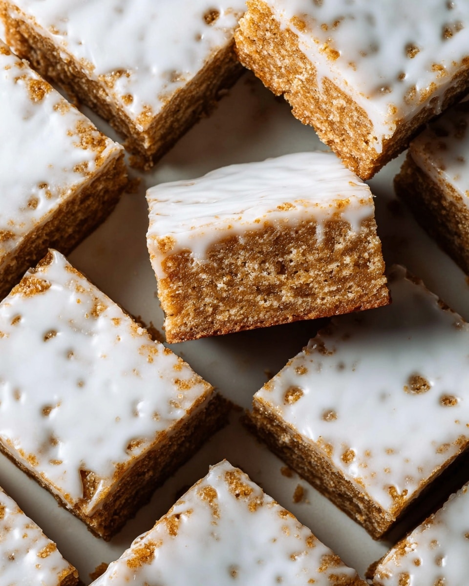 The image shows several square bars arranged closely together on a white marbled surface. Each bar has two main layers: a bottom layer with a crumbly, brown, textured look and a top layer covered unevenly with a smooth, white icing that partially drips down the edges. Some bars are stacked, revealing the thickness of the brown base and its grainy texture, while the white icing layer appears thin and glossy. The overall color contrast between the light brown base and the bright white icing creates a simple yet inviting appearance. photo taken with an iphone --ar 4:5 --v 7