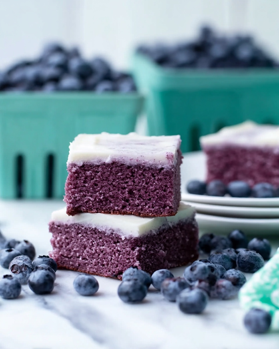 Two square pieces of moist purple cake are stacked in the center; each has a smooth white frosting layer on top. The cake texture looks soft and dense. Around the cake, fresh blueberries are scattered on a white marbled surface. In the background, there is a white plate with more pieces of the purple cake topped with white frosting, and a green carton filled with blueberries. The setting is bright and clean, highlighting the cake and blueberries. photo taken with an iphone --ar 4:5 --v 7